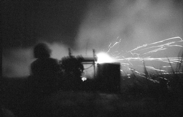 View from behind of a Chinese National Marine firing a gun at night in Laos.
