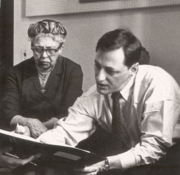 Eleanor Roosevelt and Millard Lampell are seated together looking at a notebook or script.