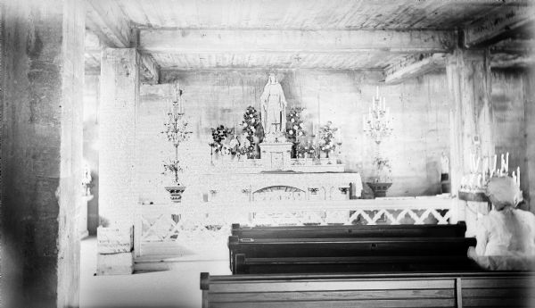 Interior view at Holy Hill over pews towards a shrine. A woman sits in one of the pews on the right.