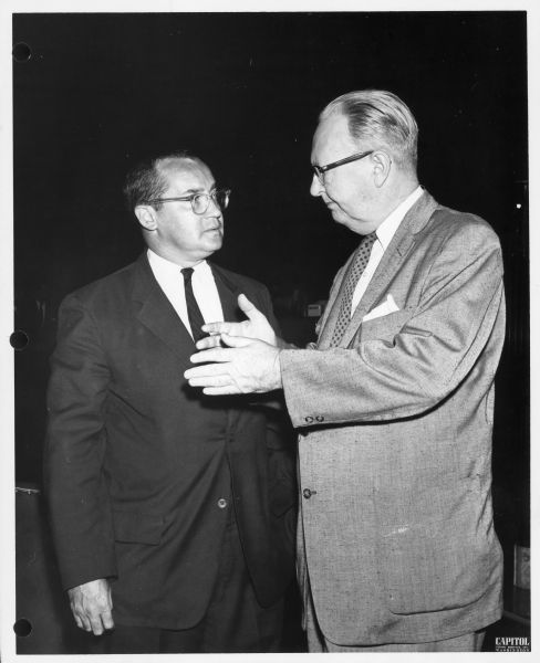 Newton Minow stands with another man, who is standing sideways and gesturing.