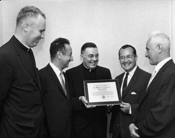 Newton Minow, second from the right, poses with other men, holding a plaque.