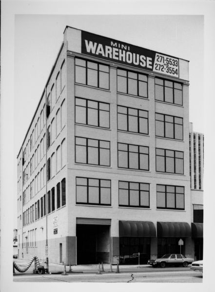 Exterior view of the Wellauer building at 712 East Michigan Street. There is a large sign at the top of the building that reads: "Mini Warehouse."