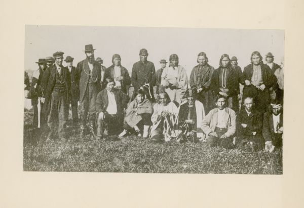Group portrait of members of the La Pointe Band (now known as the Bad River La Pointe Band) of the Ojibwe Nation awaiting annuity payment at La Pointe. None of the people are identified.