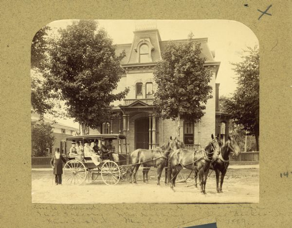 Group portrait posed in a horse-drawn carriage outside the David Atwood House, at 204 Monona Avenue. Caption on back of photograph reads: "Group of ladies in horse-drawn omnibus posed in front of mansard brick home, 1889. Uncle Atwood stands by bus. The ladies are Ms. Atwood, Ms. Pope, Ms. Gregory, Mrs. Hibbins, Mrs. Bishford, Miss Rusk, and Ms. Scidmore. Driver is unidentified."