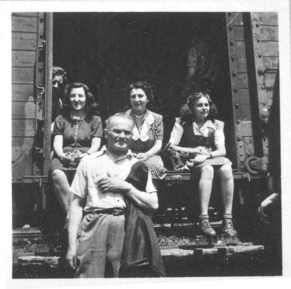 The Weinschenker family posing in the doorway of a train car. Standing in front of the group is Chaim Weinschenker. Behind him, from left to right, are an unidentified woman, Klara Weinschenker and Frieda Weinschenker. They are about to travel to Bremerhaven, Germany to sail to the United States.