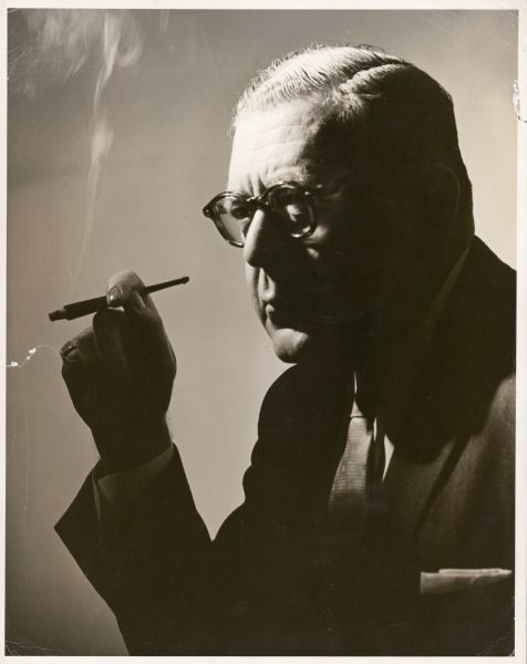 Dramatic waist-up portrait of an older Leo Lania (born Lazar Herrmann) holding a cigarette in a holder.