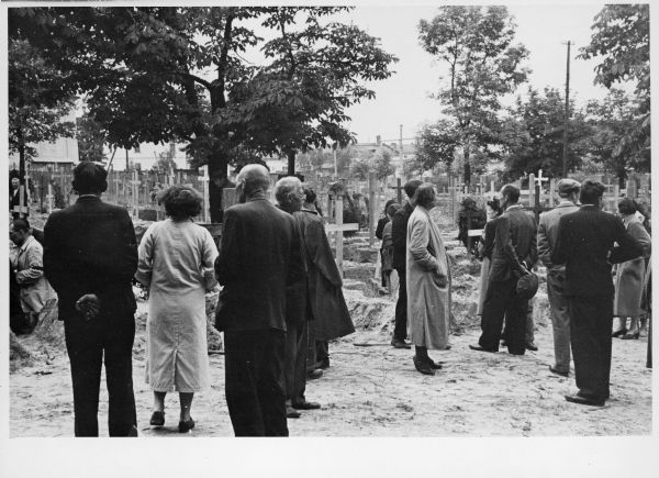 A group of people stand in a graveyard in Lemberg, Poland as German victims of a massacre are buried.