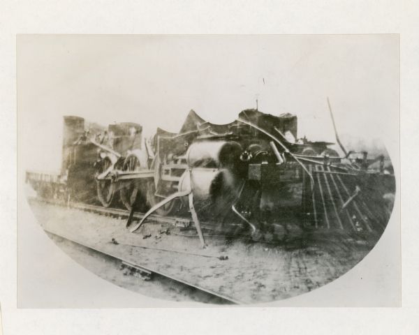 Three-quarter view from front right of the badly damaged Engine No. 423 of the Chicago, Milwaukee and St. Paul Railway. The boiler remains on the railroad tracks after its boiler exploded and shot out from the locomotive.