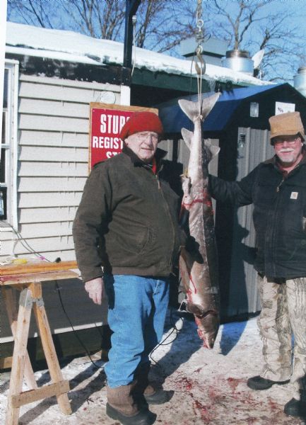 Bill Casper (left) with the last sturgeon he speared at a DNR registration station near Lake Winnebago. He is joined by his cousin, Paul Langenfeld (right).