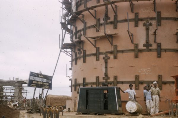 Group of men posing in front of a structure on a steel plant construction plant in Bhilai, India.