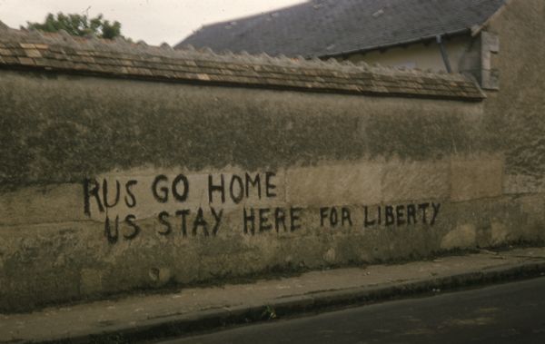 Graffiti on wall which reads: “RUS GO HOME, US stay here for liberty.” In Europe, probably France or Germany.