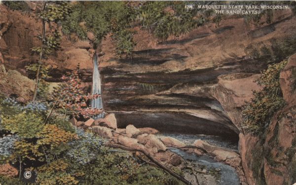 Postcard for Marquette Park in Grant County, number 4706 in a series by E.A. Bishop of Racine. The caption on the back of the postcard reads: "The picturesque rocky gorge beginning at the banks of the Wisconsin River and extending far into the interior of the Park is enchanting and compels our attention. Here in the forest, amid blossoms and ferns, nature has chiseled from the sand rock large semi-circular caves, displaying strata of sand of every hue, while over the crest of the gorge a silvery cascade places the finishing touch to a bit of wild woodland scenery which will be deeply impressed upon our memory."