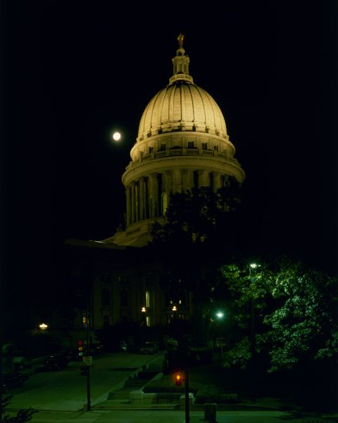 Wisconsin State Capitol at night with moon in background.