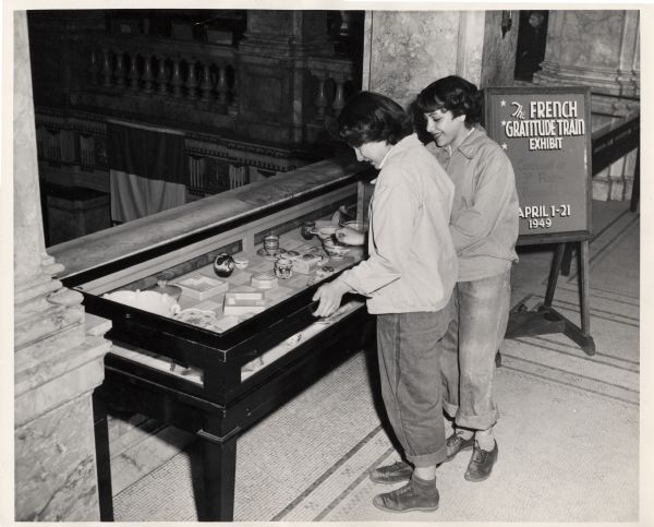 Two young women look at a display case containing items from the French Gratitude Train on exhibit in the Milwaukee Public Library.