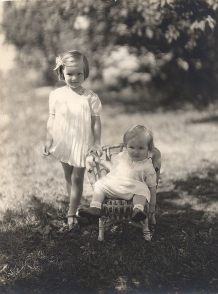 Informal, outdoor portrait of Victor Berger's grandchildren, Deborah and Polly Welles. Polly is seated in a small chair.