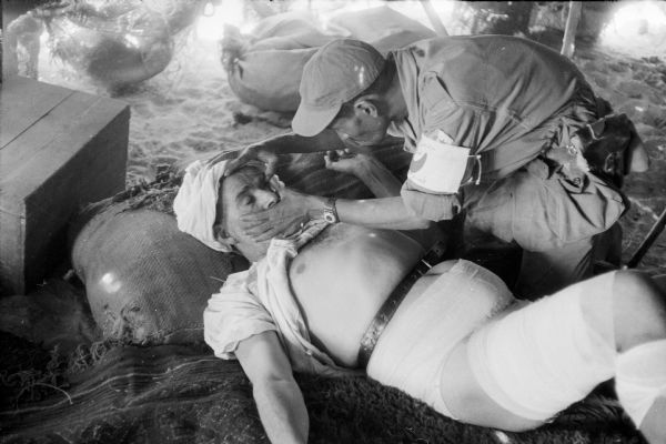A Red Crescent doctor examining an injured man who is wrapped in bandages. They are in Algeria.