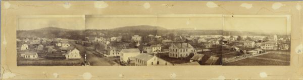 Sepia-toned elevated panorama, built from four separate photographs, of Sauk City. The Wisconsin River is in the background, with large hills on the other side of the river.