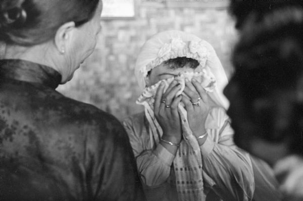 Anh Le Vuong weeps into her handkerchief during her wedding to Tien Vinh Le in Binh Hung, Vietnam. Another woman is standing in the foreground on the left.