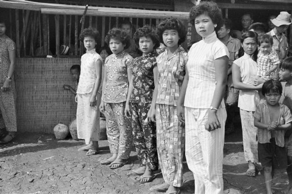 A portrait of five women, standing in a line outdoors, who are attendants of the bride at the wedding of Anh Le Vuong and Tien Vinh Le in Binh Hung, Vietnam.