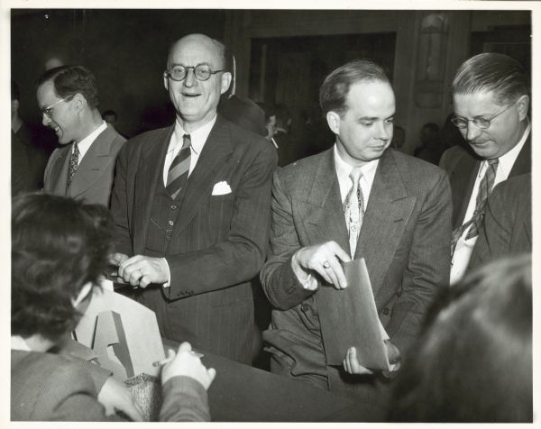 Reinhold Niebuhr, who is smiling and wearing round eyeglasses, stands with several other men, probably at an Americans for Democratic Action event.