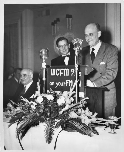 Reinhold Niebuhr speaking into a radio microphone for the station WCFM at a dinner for Franklin Delano Roosevelt.