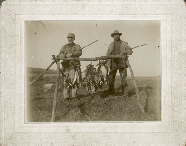 Walter Stock (left) and Louis Fauerbach posing during a duck hunting outing at Cherokee Marsh. They are holding rifles and standing near the ducks they shot.