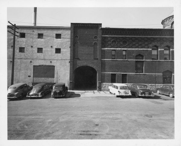 View from Blount Street looking west of Fauerbach Brewing Company, including a large, arched entry. There are several cars parked by the building.