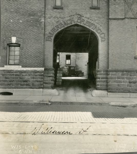 The arched doorway of the building which housed Fauerbach Brewery at 653 Williamson Street. The name of the brewery is displayed on the arch. Through the arch a truck can be seen parked in the courtyard.