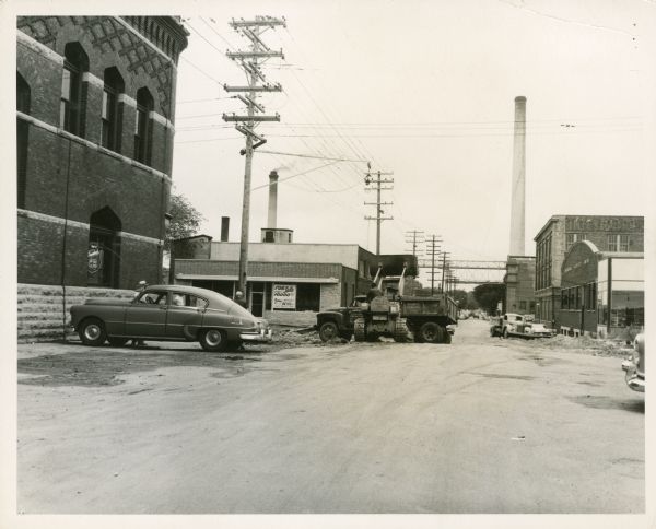 View down South Blount Street with smokestacks in the background. Fauerbach Brewery is on the left. Several trucks and a car are parked on the street. 