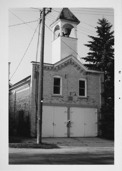 View across street towards the Waubeka firehouse at 401 Center Street. In a tower above the entrance is the Red Arrow siren, which has since been removed. 