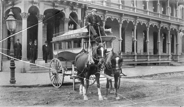 View from the street of a man holding the reins for a team of two horses and sitting in the driver's seat of the Omnibus Line in front of the Park Hotel on Carroll Street. A group of men stand on the porch steps.

"This omnibus was driven by an employee of Beverly Jefferson Transfer Line, which maintained one of the largest companies of carriages, hacks, and wagons in this section of the country." -- from History of Dane County, p. 813 in Stanley C. Hanks Collection Notes PH 6095.

Beverly Jefferson, for forty years was the the owner and manager of an important transfer line at the Wisconsin capital.  He had lived at the Park hotel for 25 years, dying in 1908 at the home of his son in Chicago. He was 1/16 African-American.