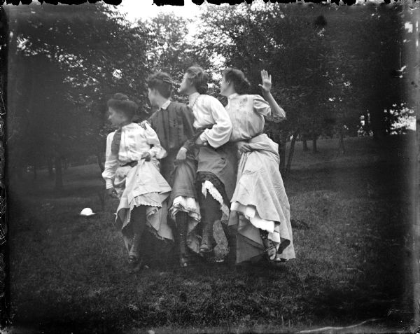 Four young women dancing outdoors in a synchronized line, probably at Rock Spring Park.
