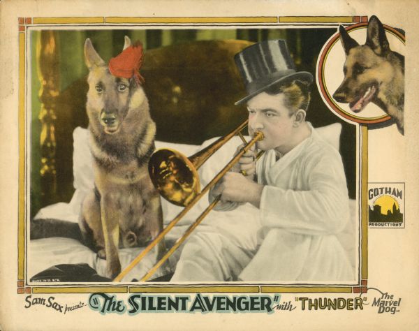 Lobby card for the film "The Silent Avenger." A man in pajamas and wearing a top hat is sitting on a bed playing a trombone. Thunder the dog is sitting next to him wearing a small red hat.