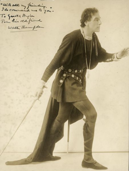 Walter Hampden posing in costume as Hamlet. He is holding a sword pointing down to the floor in one hand. There is a dedication and autograph to Gareth Hughes from Hampden in the top left corner.