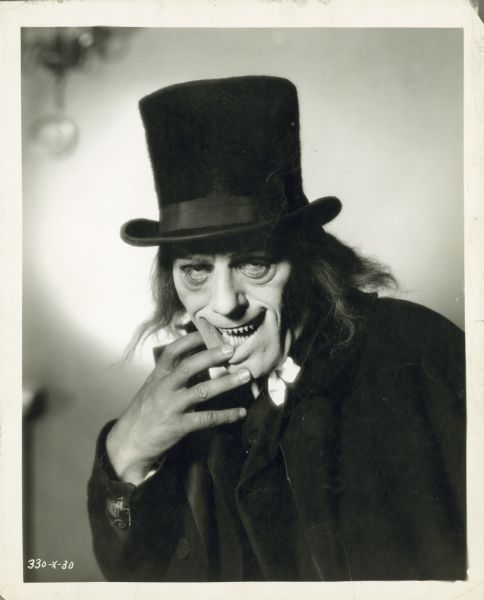 Lon Chaney in one of his disguises for the film "London After Midnight." Chaney is wearing sharpened vampire teeth, long hair, and a top hat. 
