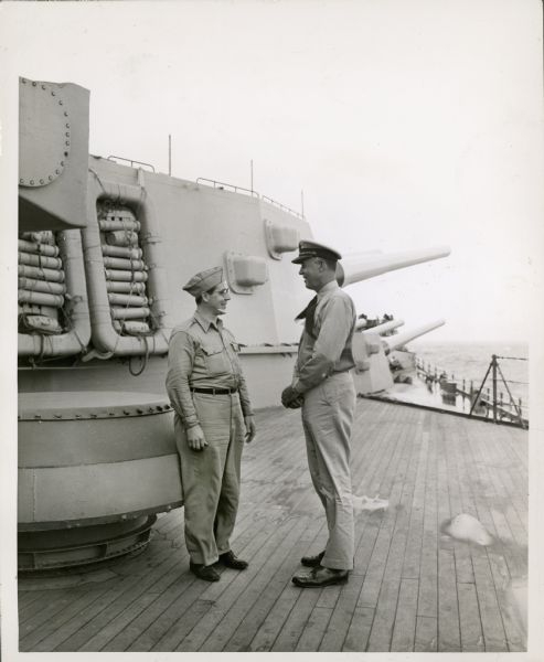 John MacVane (left) standing and talking with another man on the deck of the "USS Missouri" in the Panama Canal.