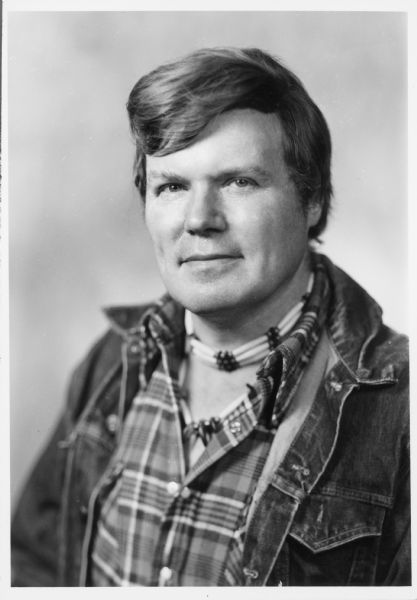 A portrait of John R. Salter, Jr. He is wearing a beaded necklace and a denim jacket.