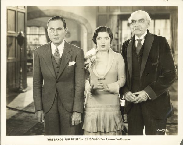Herbert Willis (Owen Moore), Molly Devoe (Helene Costello), and Sir Reginald Knight (Claude Gillingwater) standing next to each other. Willis has a blank stare on his face, Devoe is looking shocked, and Knight is looking angry. The men are both wearing monocle's.