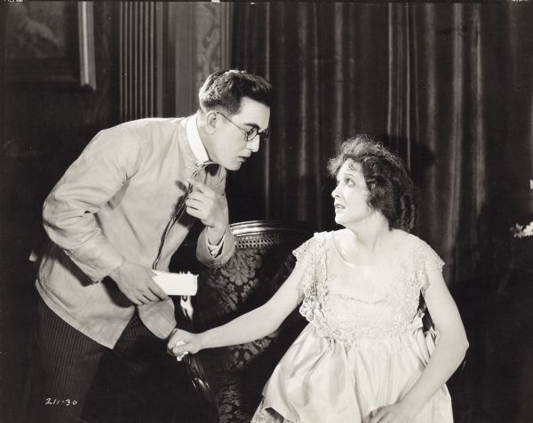 Hashimura Togo (Sessue Hayakawa) is leaning towards Corinne Reynolds (Florence Vidor) who is sitting, in a scene from the 1917 film "Hashimura Togo." She is looking up at him with a worried look on her face.