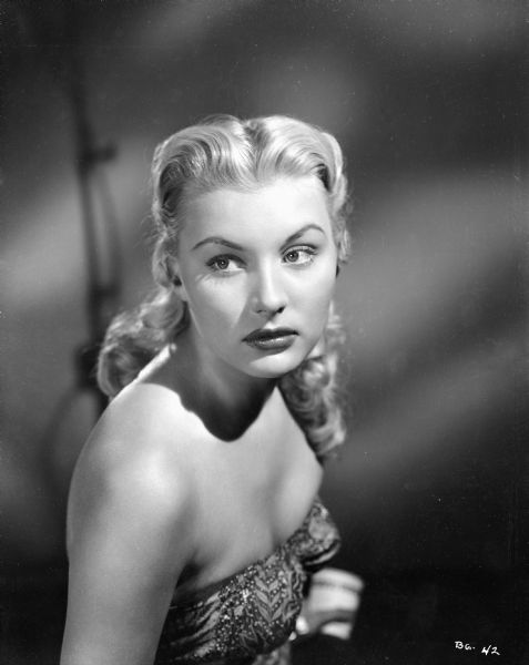 Publicity still of actress Barbara Payton for the film "Bride of the Gorilla." She is wearing a sleeveless gown.