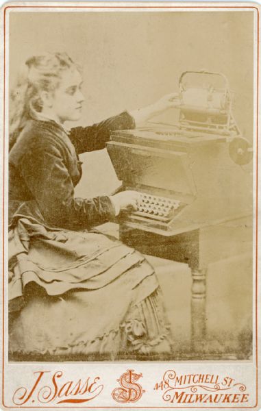 Lillian Sholes, demonstrating a prototype typewriter invented by her father, Christopher Latham Sholes.