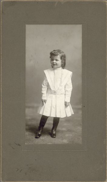 Studio portrait of James Larnard Liddle (1900-1919) wearing a white cotton dress with black stockings and shoes. He has shoulder-length hair.

James was born February 2, 1900 in Delavan (Walworth Co.), Wisconsin, the son of Harry Hobart Liddle (1870-1934), a confectionary store merchant, and Edna (Larnard) Liddle (1868-1925). James joined the US Navy in December 1917 and died of pneumonia on September 27, 1919 when stationed at Puget Sound, Washington.