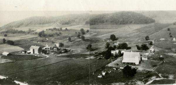 Aerial view of two farms, with fields and barns in a valley. This image appeared in Joseph Schafer's 1932 book <i>The Wisconsin Lead Region</i>, on a photographic page between pages 230 and 231. It has the following caption: "Broad, fertile valley, bordered with heavily wooded bluffs, town of Castle Rock, Grant County, Taken from bluff above County Trunk G, 1930."  