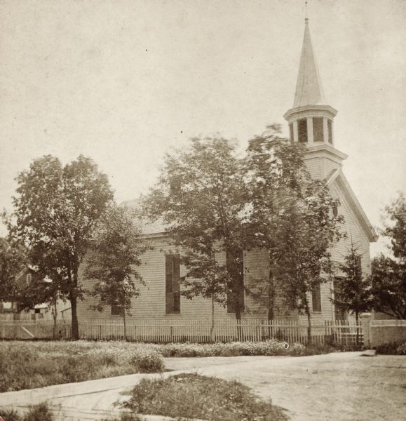 Stereograph view of the exterior of Assembly Presbyterian Church, surrounded by trees.