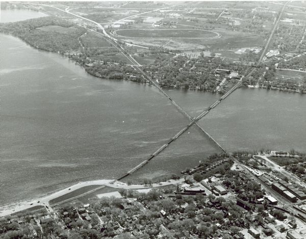 Aerial view over Monona Bay showing two railroads crossing in the center. Olin Park is on the top left. 