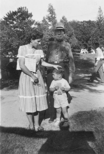 H.M. Clark posing outdoors with his wife and young child.