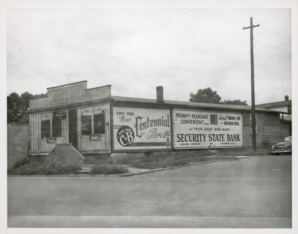View across street towards the Atwood Alleys bowling alley, 2164 Atwood Avenue, owned and operated by William Freund. There are advertisements for Centennial Brew and Security State Bank on the side of the building.  The bowling alley was in operation ca. 1920-1950.