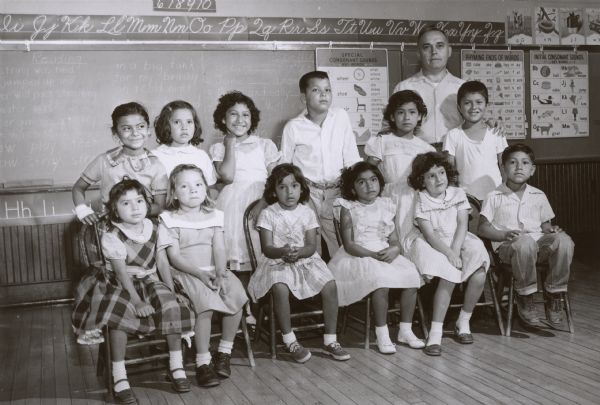 Caption on back: "Lester J. Kornely, teacher of the summer school for migrant children, poses with some of the pupils enrolled from the three migrant camps in Manintowoc County."