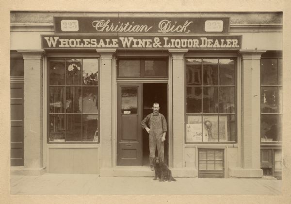 View towards Christian Dick and his dog posing in the entryway to his wine and liquor store at 223 State Street.