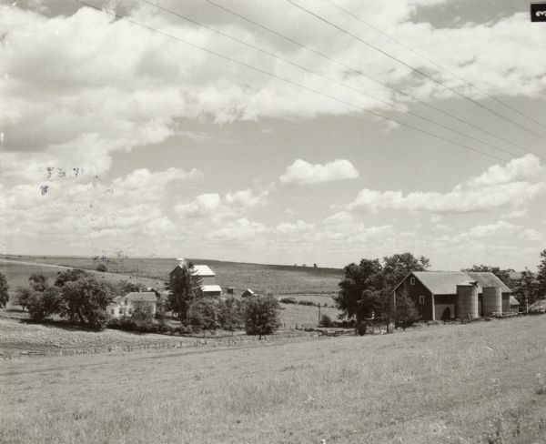 View from slope towards a farm, with barn, silos, and farmhouse. Caption reads: "Mt. Horeb (Vicinity) Wis. Highway 92, c. 1951-1955."